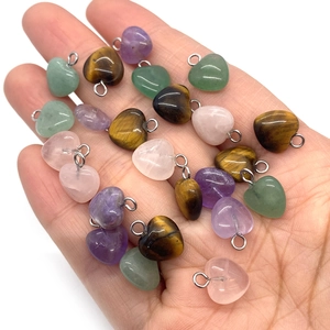 Natural heart-shaped gemstone pendants including tiger eye and amethyst in hand