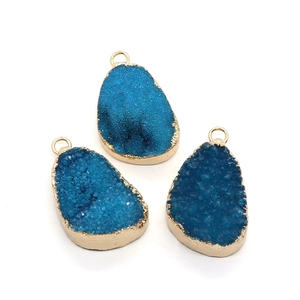 Drie onregelmatige kristallen hangers met blauwe druzy textuur en gouden metalen randen