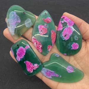 Hand holding five natural agate stone pendants in various shapes with drill holes