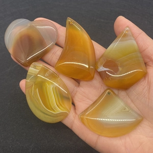 Dettaglio macro di cinque ciondoli in agata gialla naturale a forma di cuore per fai-da-te