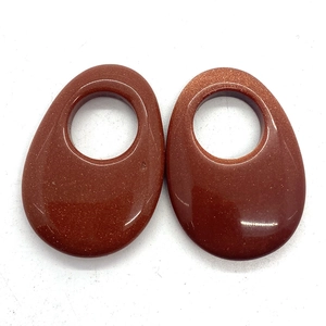 Detail of oval goldstone pendants with glittering finish and hole for DIY jewelry