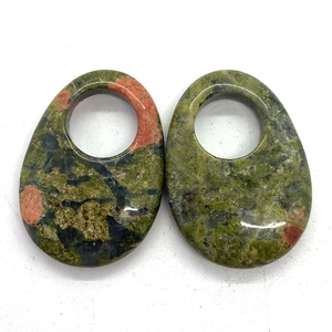 Macro view of polished teardrop unakite pendants with circular cutouts and unique textures