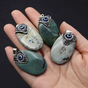 Close-up of natural turquoise stone pendants with diamond-set evil eye metal charms