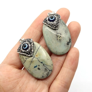 Natural oval turquoise pendant with evil eye design and rhinestones on a silver bail