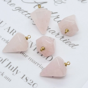 Cinque pendenti geometrici a piramide in quarzo rosa con anelli d'oro su carta