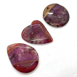 Detailed view of polished agate stone pendants in vibrant purple and orange for DIY jewelry