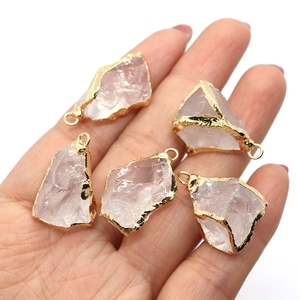 Pendenti in cristallo rosa naturale con bordo placcato oro tenuti in una mano
