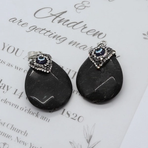 Detail of two teardrop black agate evil eye pendants with silver rhinestone buckles