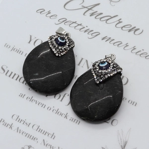 Detail of teardrop black onyx pendants with crystal evil eye and silver heart clasp