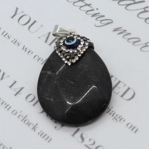 Macro detail of teardrop black onyx pendant featuring heart-shaped evil eye crystal inlay