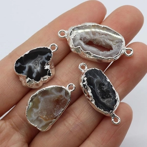 Irregular natural agate geode pendants with silver plated edges held in hand