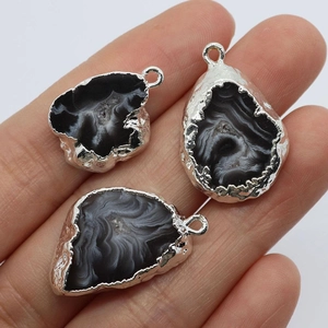 Natural agate geode pendants with silver plated irregular edges on a person's hand