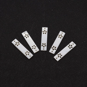 Macro detail of rectangle white shell pendants with carved hollow flower patterns