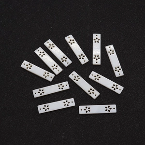 Detailed view of 11 white rectangular shell pendants with carved hollow flower patterns