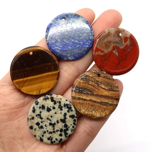Set of five natural 30mm gemstone donut pendants held in hand for jewelry DIY