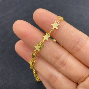 Golden twist chain with flat star pendants being held in hand for DIY jewelry making
