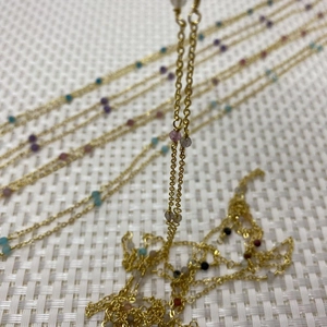 Detail of gold metal cable chain with assorted small colorful natural stone faceted beads