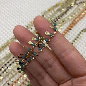 Detailed close-up of golden chain with turquoise beads and leaf-shaped pendants