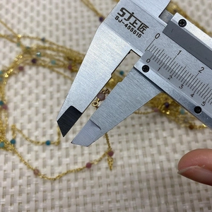 Detail showing caliper measuring 3.5mm natural stone beads on a golden copper chain