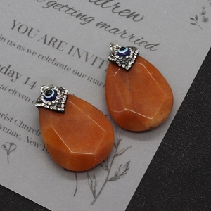 Close-up of faceted teardrop natural stone pendants with rhinestone evil eye inlay