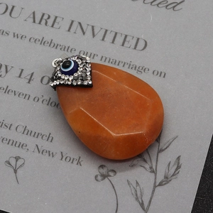 Detail of water-drop orange natural stone pendant with crystal evil eye charm connector