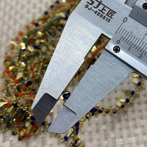 Macro detail of 2mm colorful faceted stone beads on gold chain for DIY jewelry