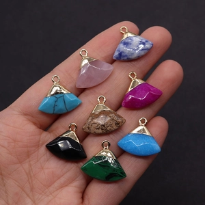 Close-up of assorted fan-shaped natural stone pendants with gold clasps held in hand
