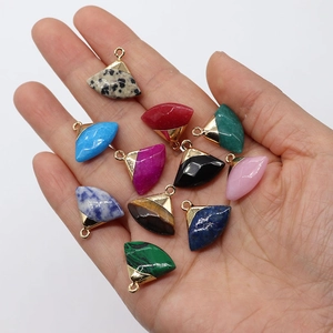 Assorted fan-shaped natural stone pendants with gold-plated loops held in hand