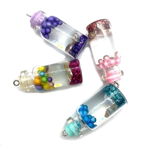 Detalle de cuatro mini botellas de deseos de cristal con cuentas de colores y conchas de mar
