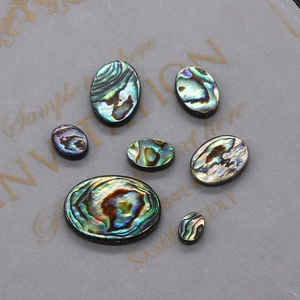 Vue macro de sept cabochons ovales en nacre d'abalone avec des éclats irisés verts et bleus