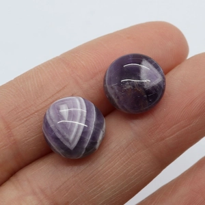 Polished 12mm purple amethyst studs held by fingers to show natural stone texture