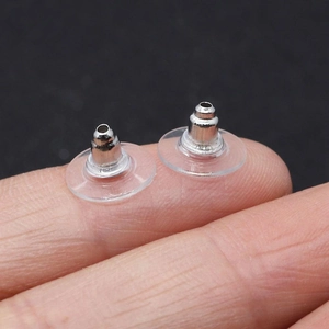 Bullet clutch ear nuts with clear plastic pads held on fingertip for size reference