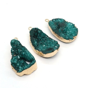 Trois pendentifs en pierre de druzy forme goutte irrégulière avec bordure dorée sur blanc
