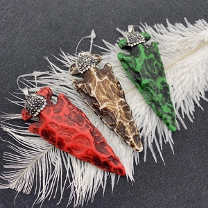 Détail de pendentifs flèches en résine avec cristaux étincelants sur fond noir
