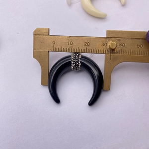Detail showing 28mm black crescent bone pendant measurement with a digital caliper