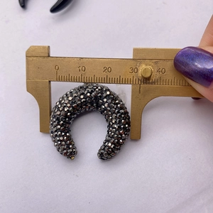 Detail view of crescent moon pendant showing 32mm outer diameter measured by caliper