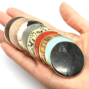 Pendentifs en pierre naturelle avec cadre doré montrés à la main pour taille et détails
