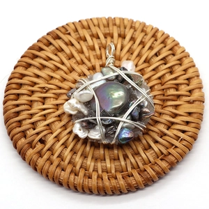 Handcrafted wire-wrapped pendant with multi-color baroque pearls on a woven mat