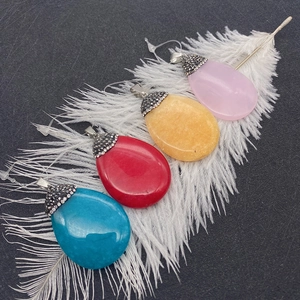 Macro detail of drop-shaped natural stone pendants with diamond-set caps and metal hooks