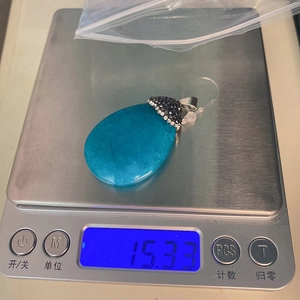 Dettaglio del ciondolo a goccia in pietra blu su una bilancia con peso di 15,33 grammi