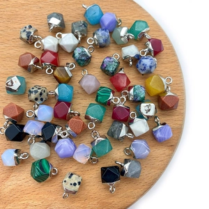Faceted natural stone pendants with metal edges in various gemstones on wooden tray
