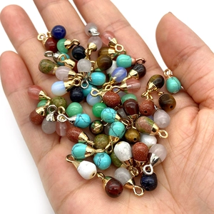 Hand holding assorted water drop gemstone pendants with gold loops for DIY jewelry making