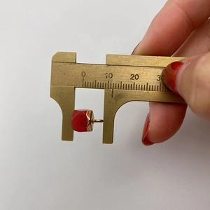 Makroaufnahme eines Natursteinanhängers mit Goldfassung, gemessen mit einem Messschieber