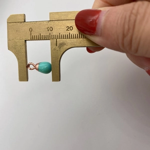 Detail view of turquoise teardrop pendant size measurement using brass vernier calipers