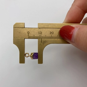 Makroaufnahme eines violetten Natursteinanhängers, mit Messschieber gemessen, 8mm Größe