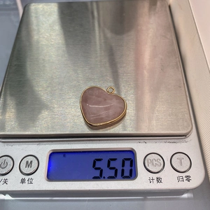 Digitale Waage wiegt einen rosa Herz-Steinanhänger mit Goldfassung, Gewicht 5,50 Gramm