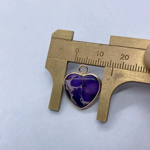 Detailweergave van hartvormige keizerlijke stenen hanger met gouden rand en schuifmaat