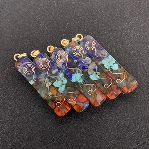 Detailed macro of rectangular resin pendants with chakra stones and metal spirals