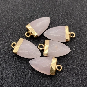 Vue détaillée de cinq pendentifs en cristal rose taillés en flèche avec embouts dorés