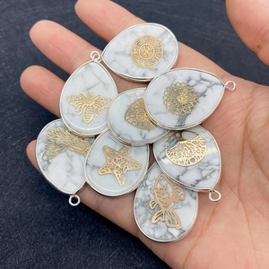 Detailed view of water drop white turquoise pendants with gold filigree animal motifs